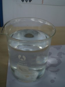 coin under beaker - with water top view